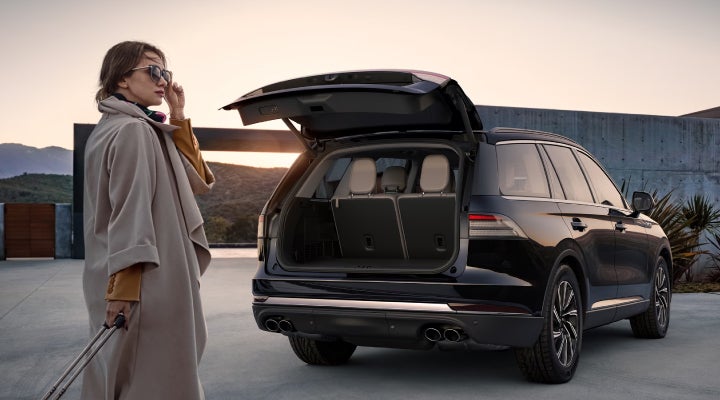 A woman approaches a 2026 Lincoln Aviator® SUV with its rear liftgate open. | Dave Sinclair Lincoln in Ballwin MO