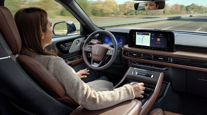 A 2026 Lincoln Aviator® SUV is being driven hands-free on a highway near a forest | Dave Sinclair Lincoln in Ballwin MO