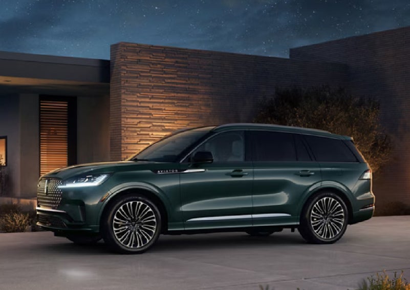 A green 2027 Lincoln Aviator® SUV is parked outside a contemporary home. | Dave Sinclair Lincoln in Ballwin MO