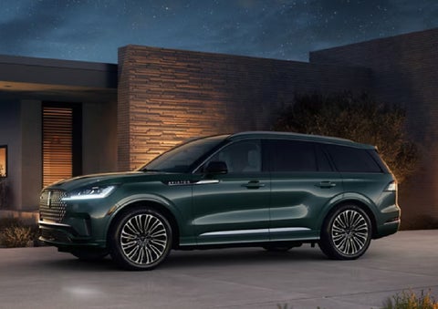 A green 2027 Lincoln Aviator® SUV is parked outside a contemporary home. | Dave Sinclair Lincoln in Ballwin MO
