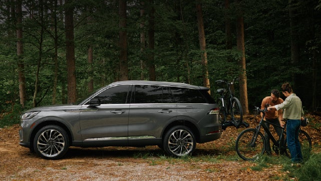 A father and son load e-bikes on a bike rack attached to a 2027 Lincoln Aviator® SUV. | Dave Sinclair Lincoln in Ballwin MO