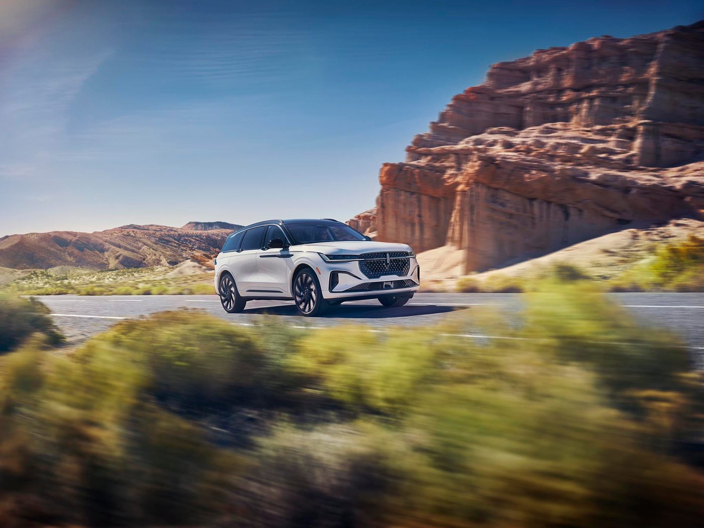 White Lincoln Nautilus driving on a desert highway past red rock formations