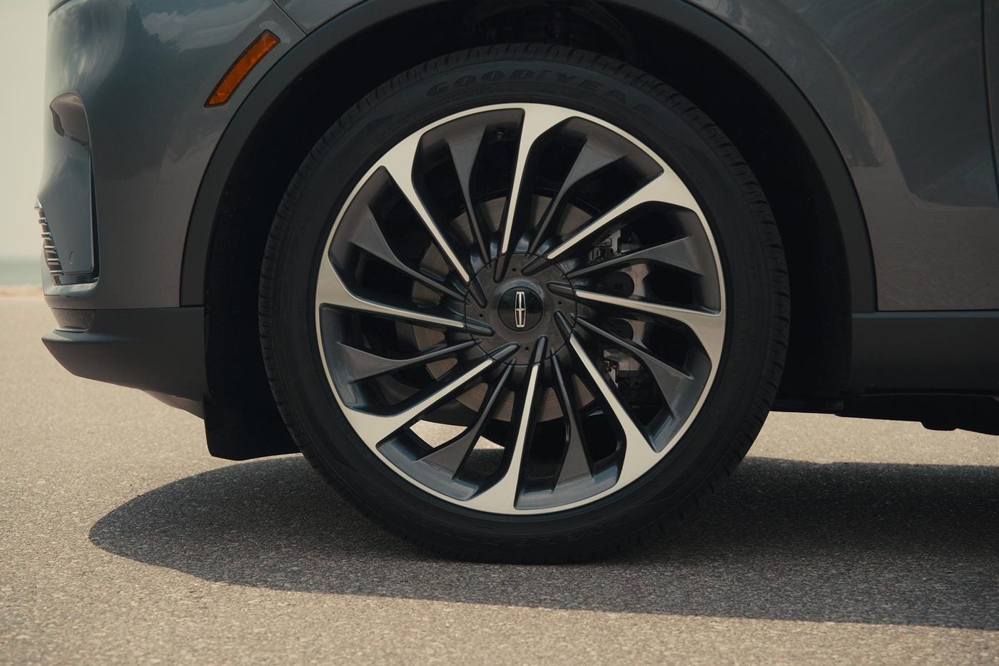 Front wheel and fender of a gray Lincoln Aviator on pavement