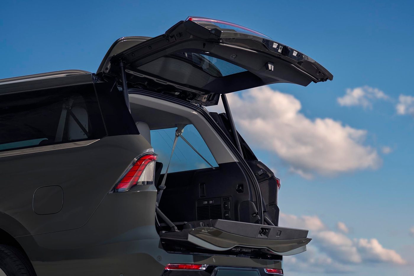 Open power liftgate and cargo area of a gray Lincoln Navigator under a blue sky