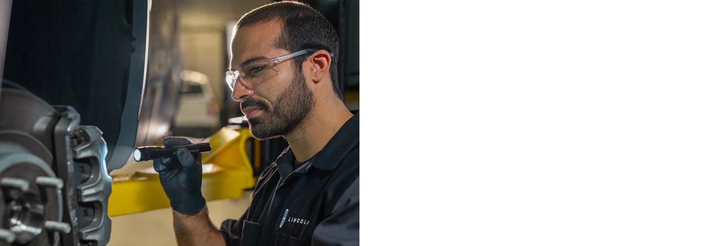 Lincoln service technician in safety glasses and gloves working on a vehicle